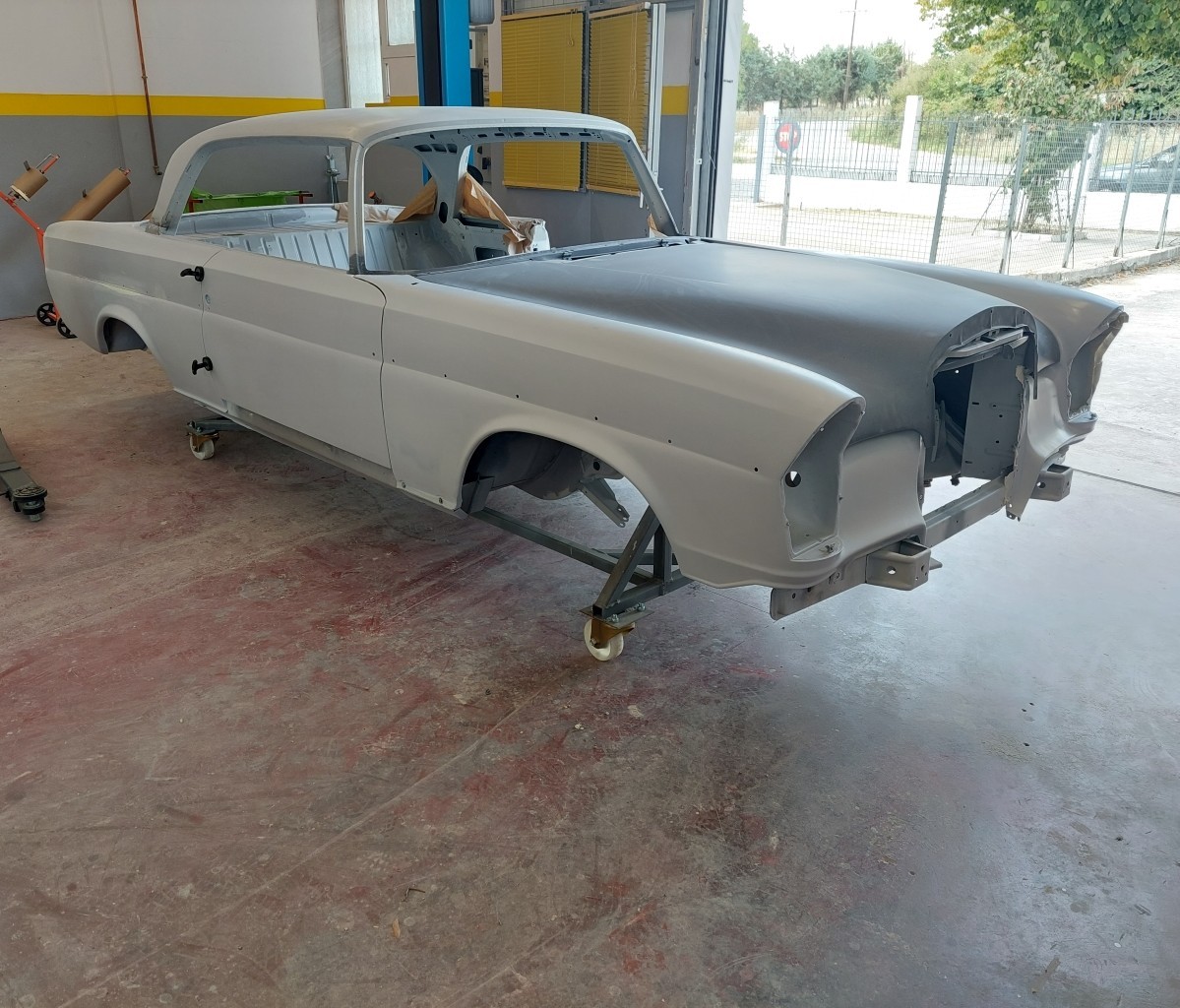 Entlackte Rohkarosserie eines Oldtimers auf einem Rollgestell